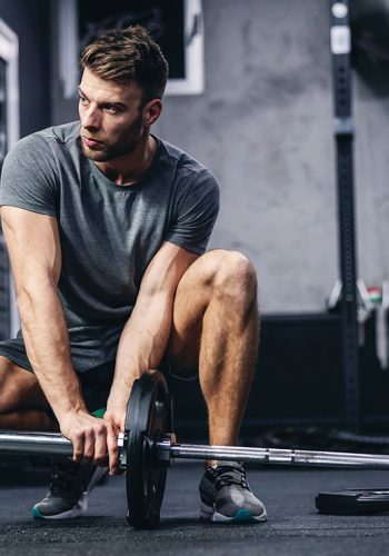 athletic male in a grey t-shirt doing landmines