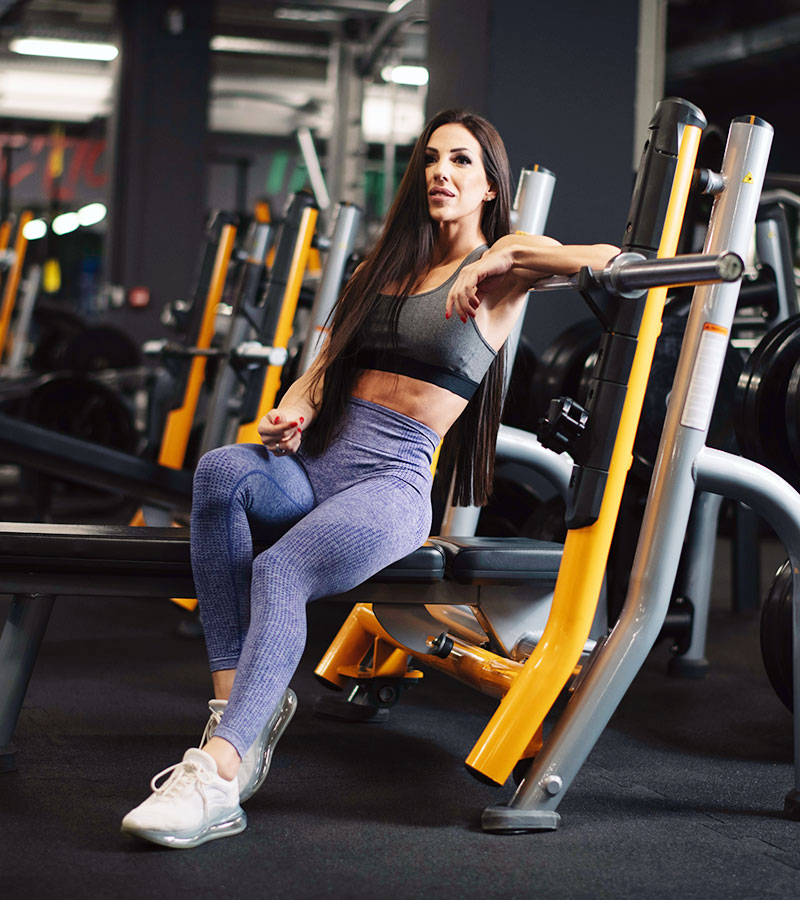 athletic girl in a grey sports bra and blue leggings posing