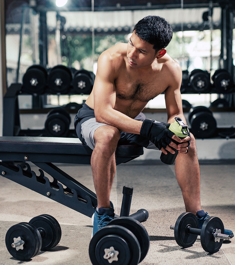 athletic guy taking a break at the gym holding a black shaker bottle