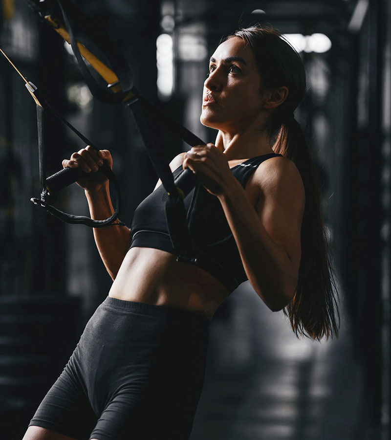 Athletic Women in Ponytail doing Cable Pull Ups