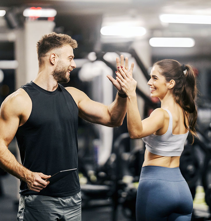 male athlete and female athlete giving each other hive-fives at the gym