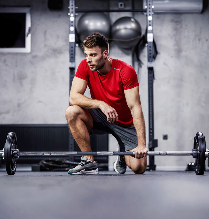 Athletic Guy in a red shirt getting ready for a deadlift